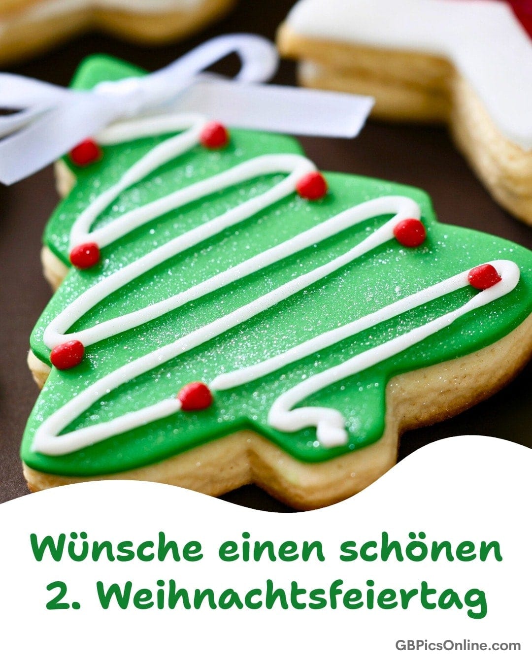 Grüner Tannenbaum-Keks mit weißer Glasur, roten Punkten und Schleife. Text wünscht frohen 2. Weihnachtsfeiertag