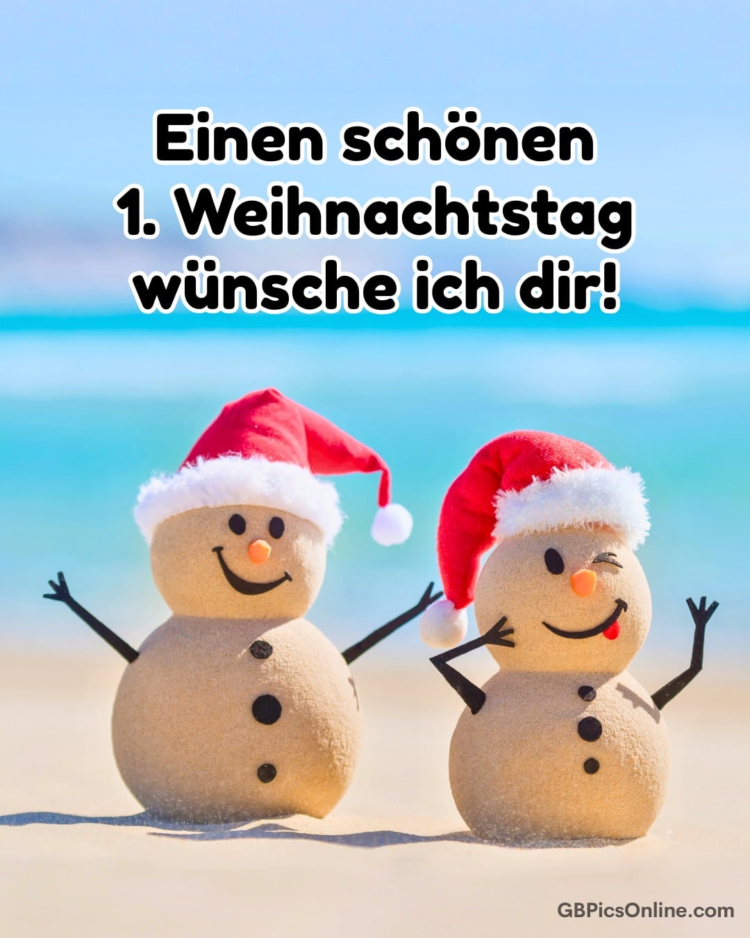 Zwei Sand-Schneemänner mit roten Weihnachtsmützen am Strand vor blauem Meer, fröhlicher Weihnachtsgruß auf Deutsch