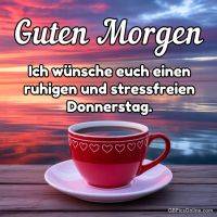 Rote Kaffeetasse auf Tisch vor farbigem Sonnenaufgang am Wasser mit Grußtext