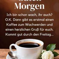 Tasse schwarzer Kaffee auf Untertasse mit Löffel, Kaffeebohnen und weißer Rose; Grußtext „Guten Morgen“