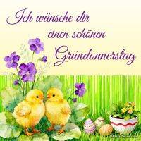 Gründonnerstagsgruß mit zwei Küken, lila Blumen und bemalten Ostereiern im grünen Gras