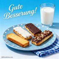 Teller mit Zwieback, teils mit Schokolade und Nüssen, daneben ein Glas Milch und Schriftzug „Gute Besserung!“
