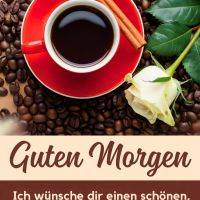 Rote Kaffeetasse auf Kaffeebohnen mit Zimtstangen und weißer Rose, dazu ein Morgengruß