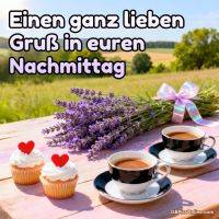 Lavendelstrauß, zwei Tassen Kaffee und zwei Cupcakes auf Holztisch vor sommerlicher Landschaft