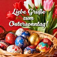 Korb mit bunten Ostereiern vor roten, weißen und rosa Tulpen auf rotem Hintergrund