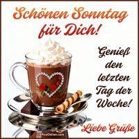 Tasse heiße Schokolade mit Sahne, Herzdeko, Schokostück und Waffelröllchen, dazu Sonntagsgruß