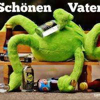 Ein grüner Plüschfrosch liegt trinkend auf einer Bank – „Schönen Vatertag“